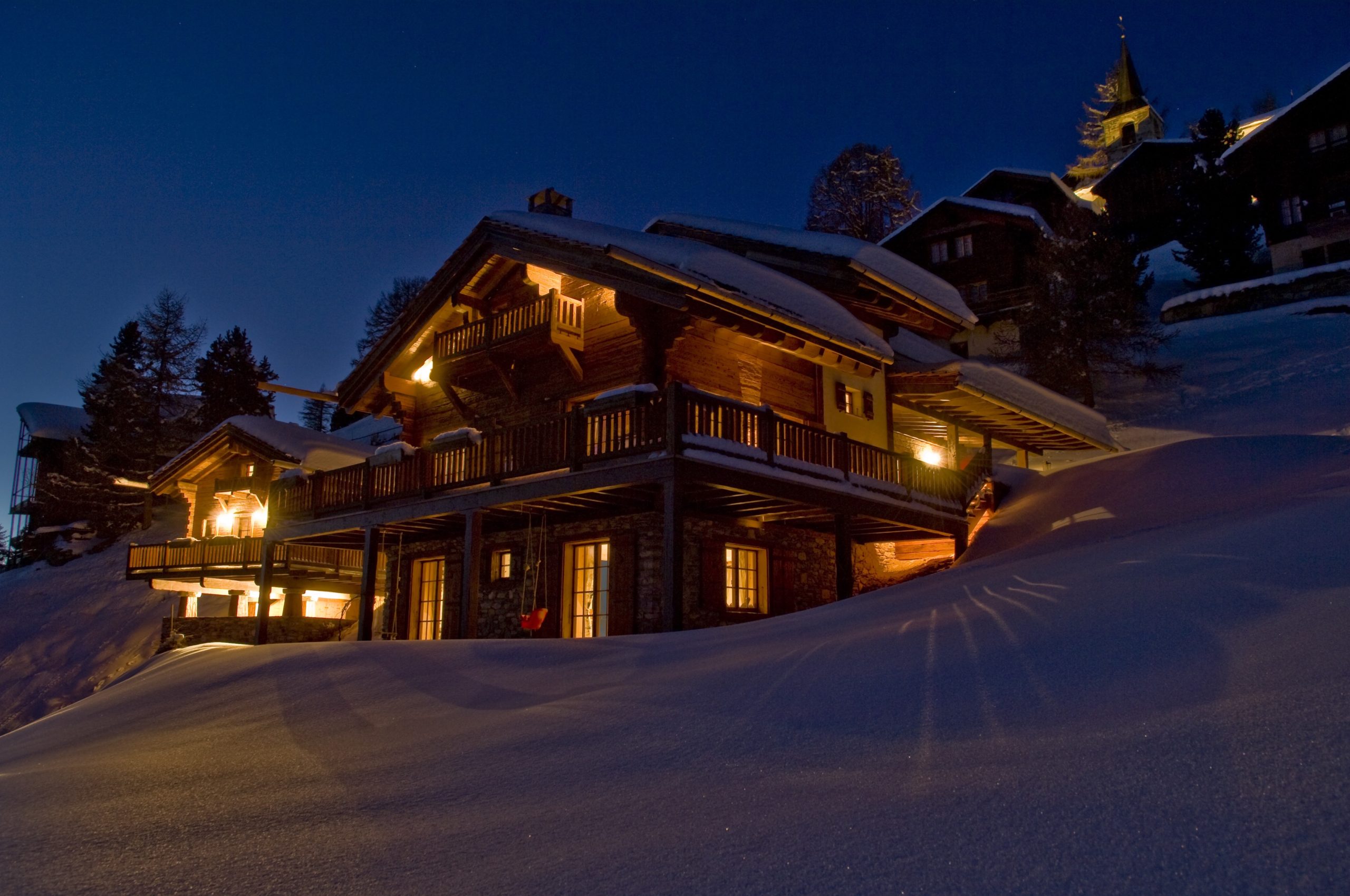 Chalet Suisse illuminé le soir avec de la neige